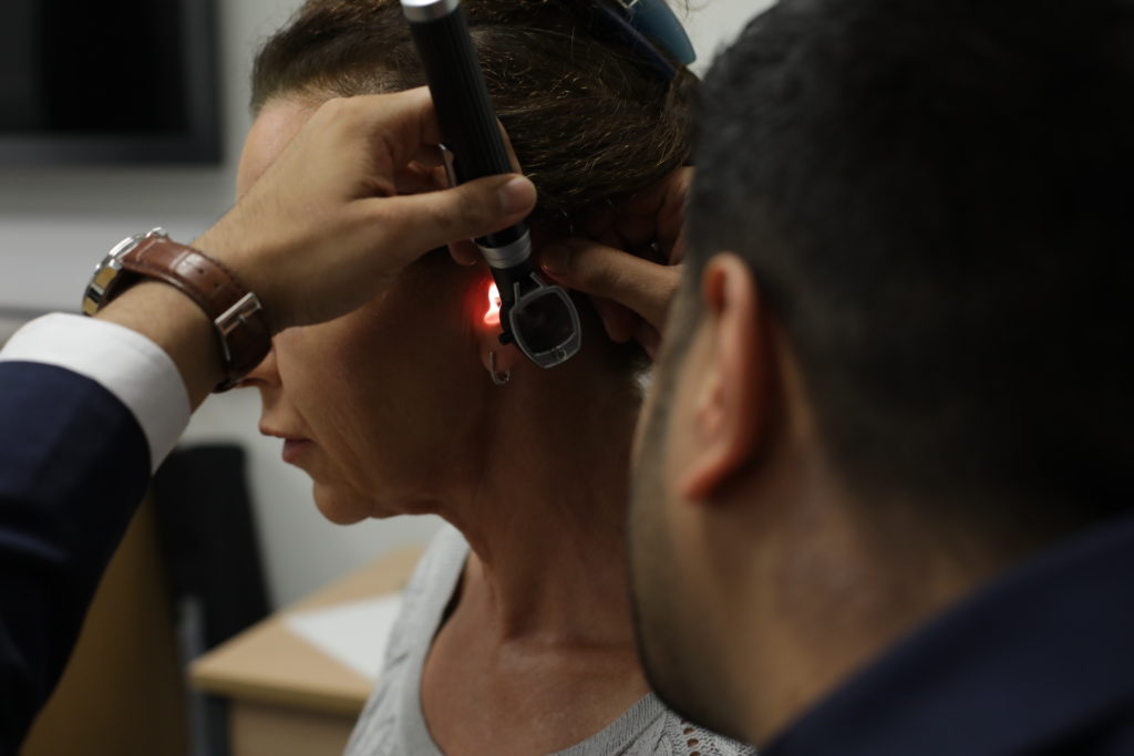 The hearing specialist inspecting an ear.