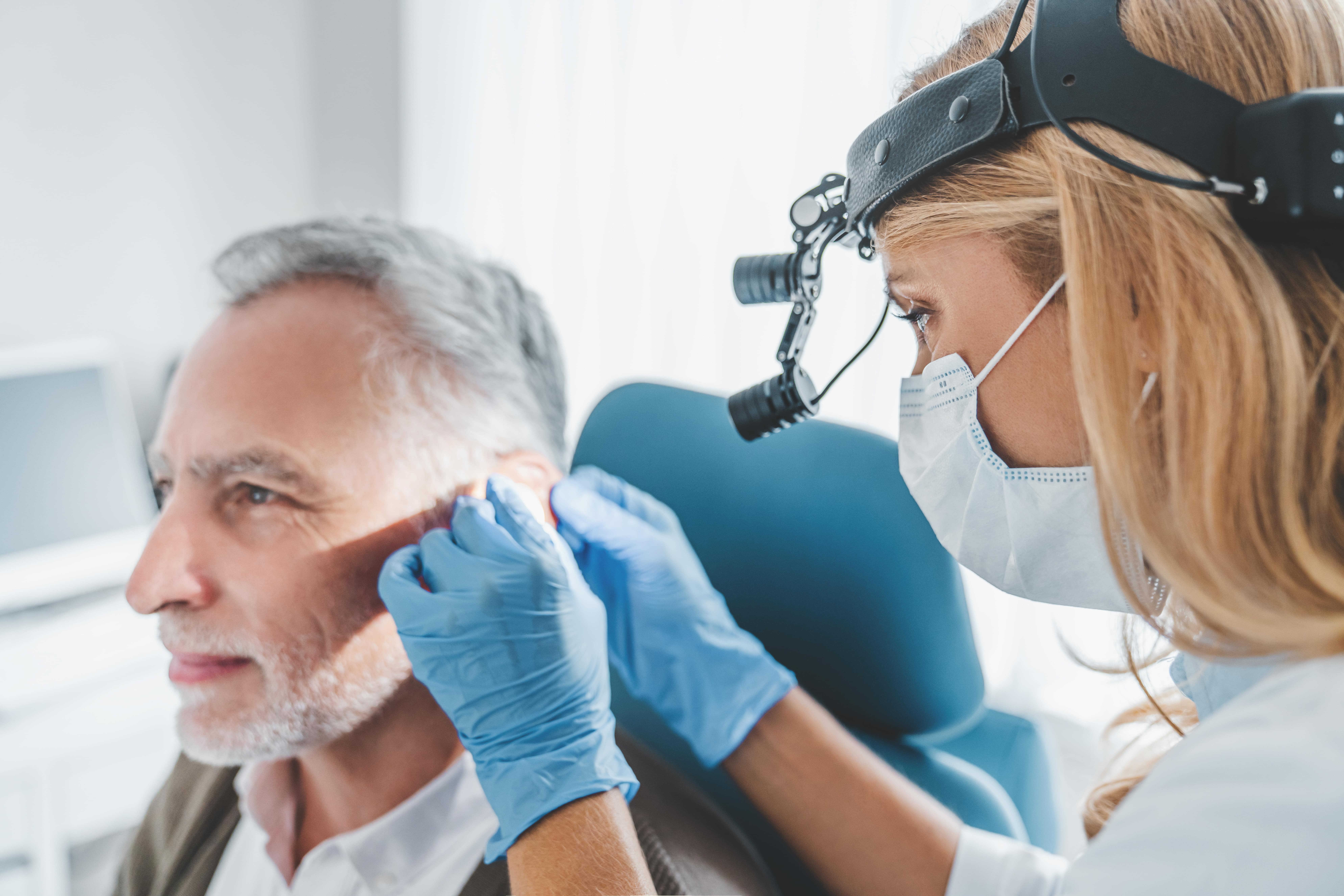Audiologist treating older males hearing loss