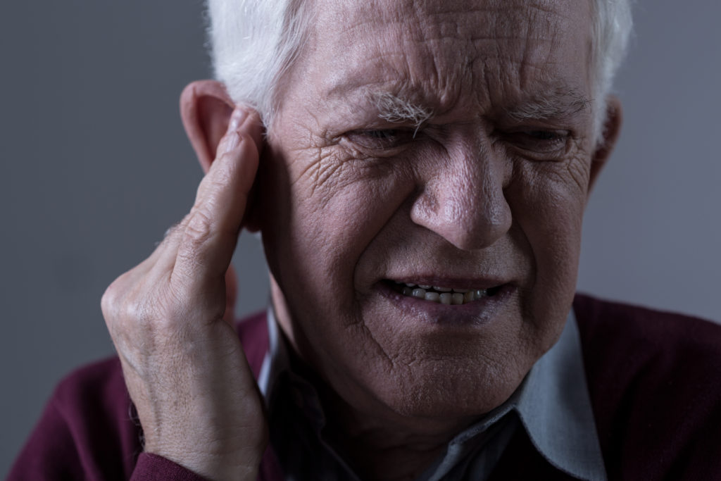 Old man in agony from tinnitus