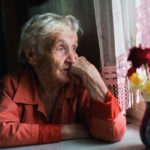 A woman sat at a window looking sad