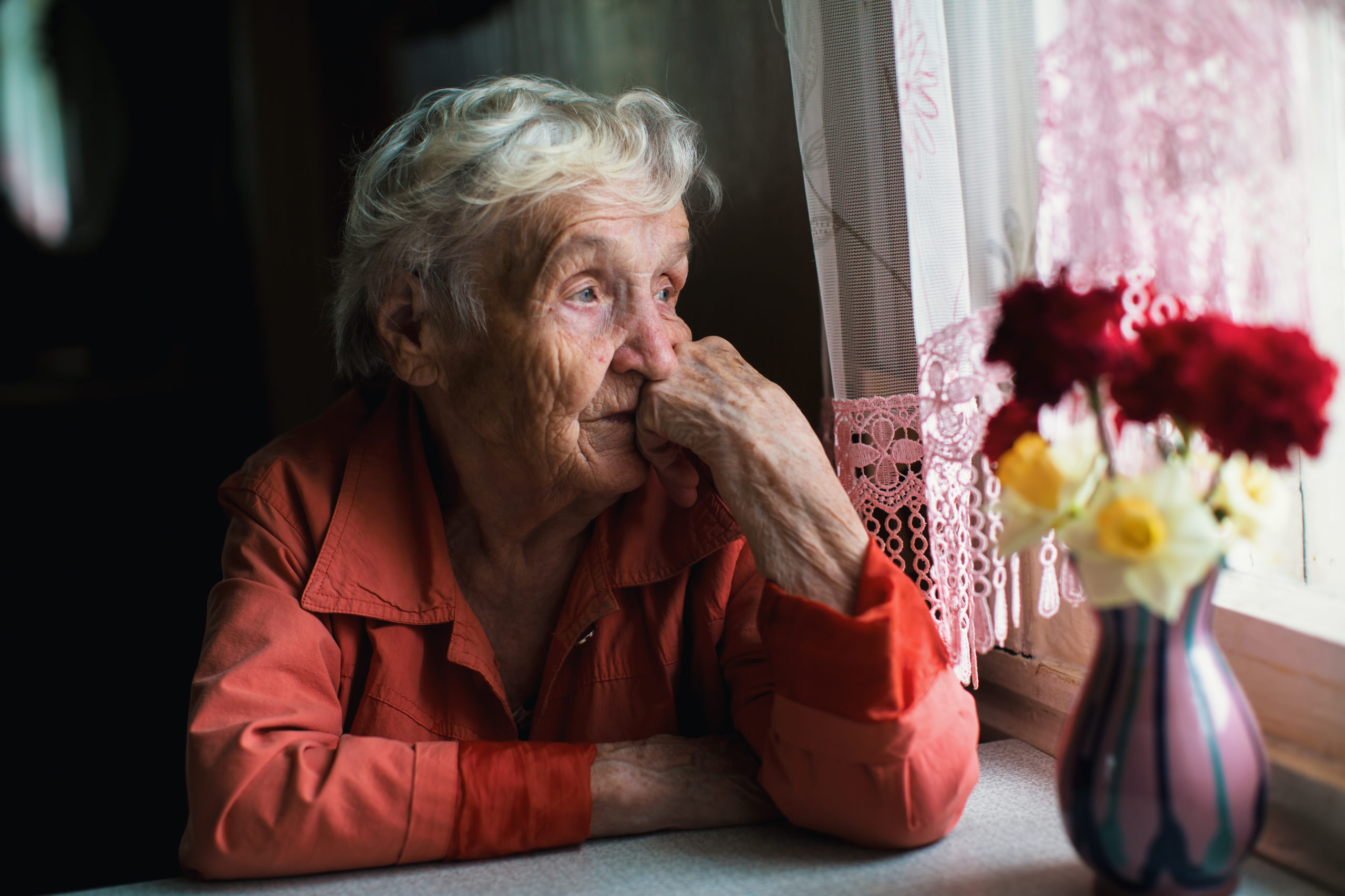 A woman sat at a window looking sad