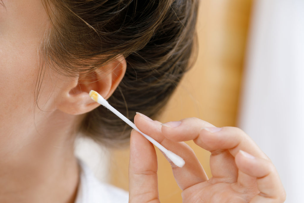 Woman cleaning her ears with a cotton bud.