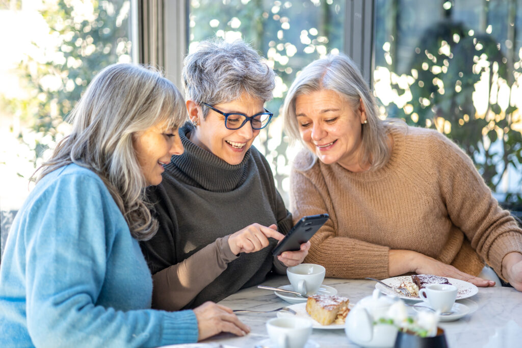 three women sat together looking at a phone