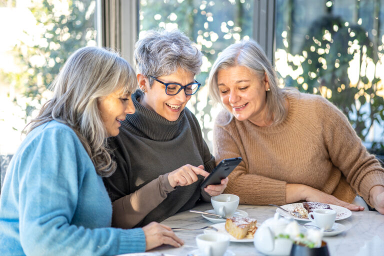 three women sat together looking at a phone