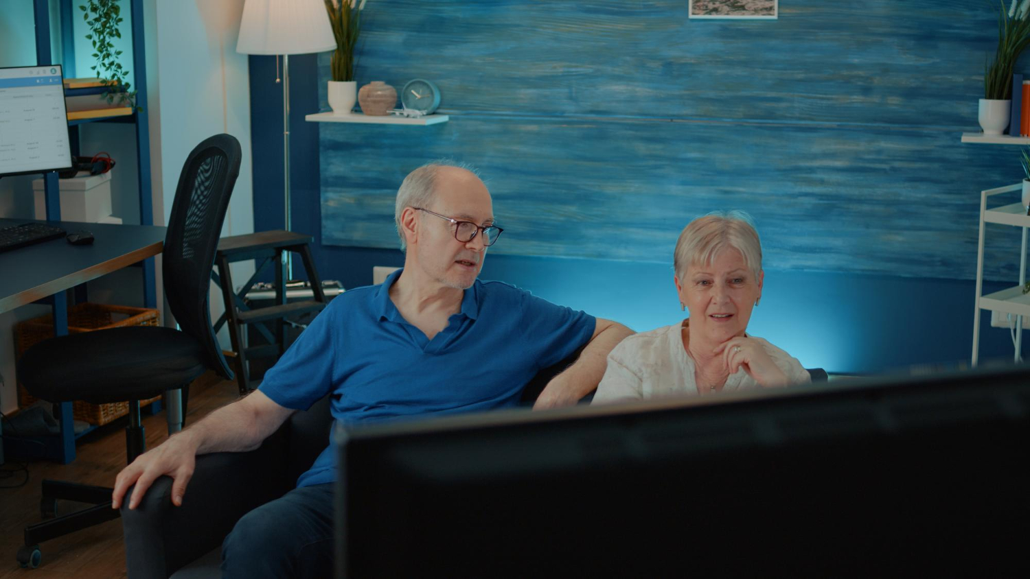 man and woman watching tv with hearing aids